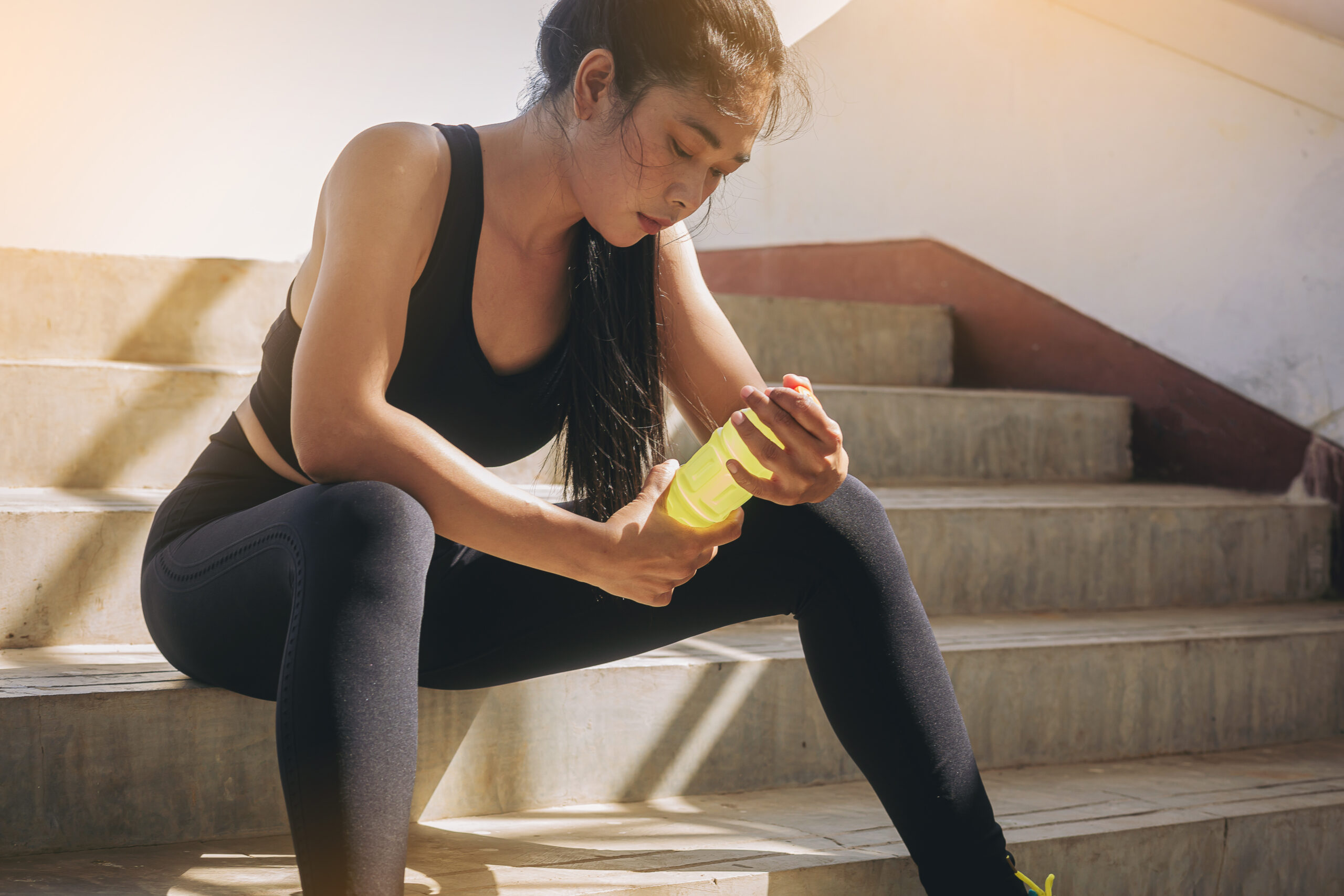 Tired runner woman with a bottle of electrolyte drink freshness after training outdoor workout at the stadium stairway. Tired runner woman with a bottle of electrolyte drink freshness after training outdoor workout at the stadium stairway.