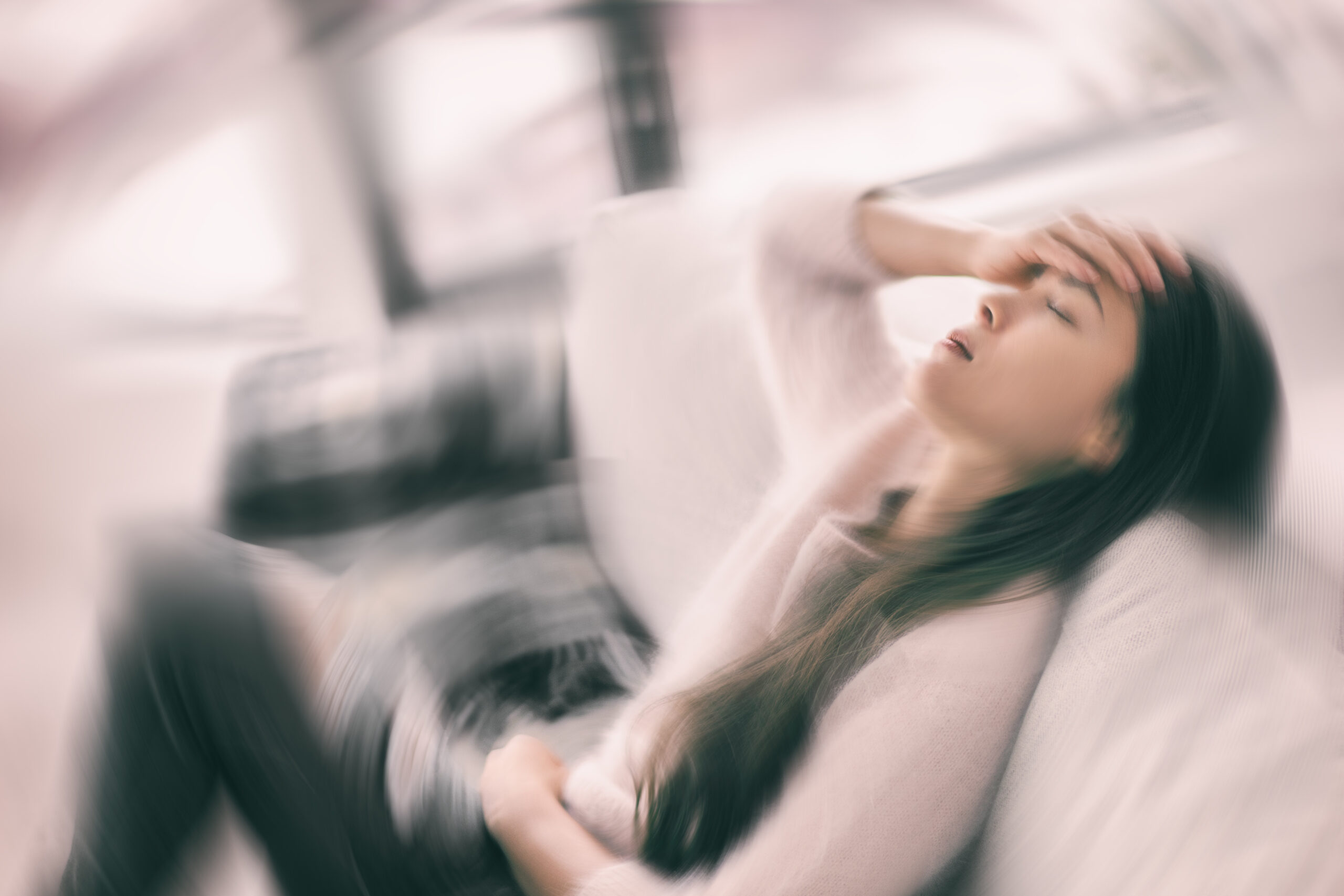 Sick woman with headache feeling faint vertigo holding head in pain with fever and migraine. Blurry motion blur background. Sick woman with headache feeling faint vertigo holding head in pain with fever and migraine. Blurry motion blur background.
